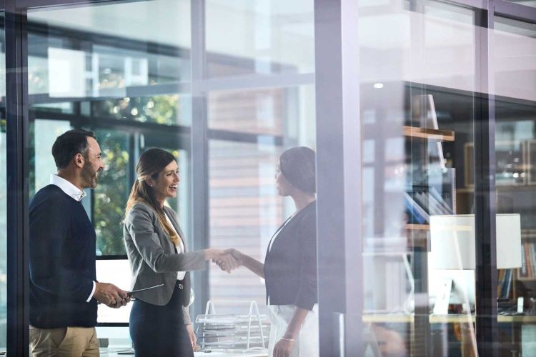 women in an office shaking hands with a man smiling