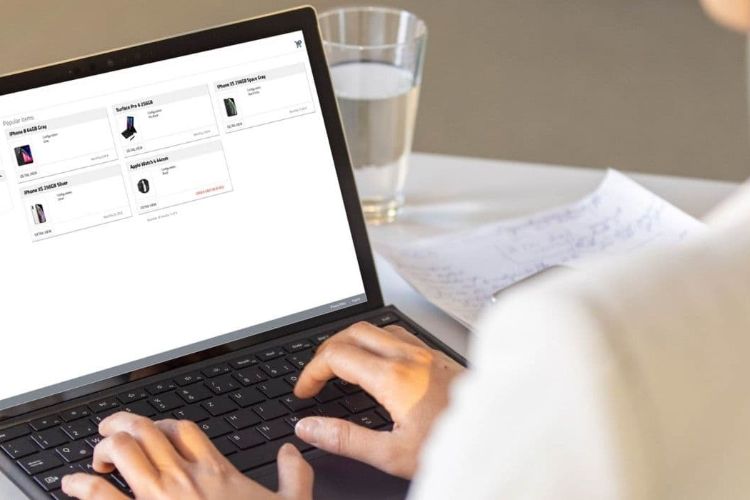 Woman on a laptop sitting at a desk with a glass of water