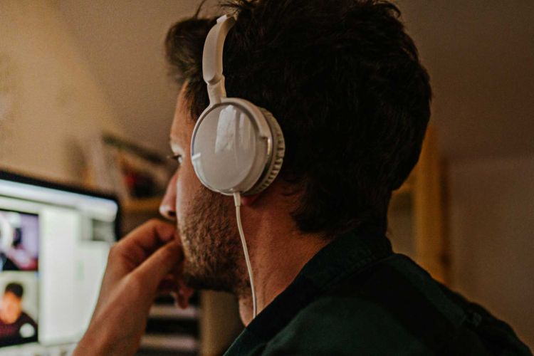 man with headphones on looking at a computer screen at home